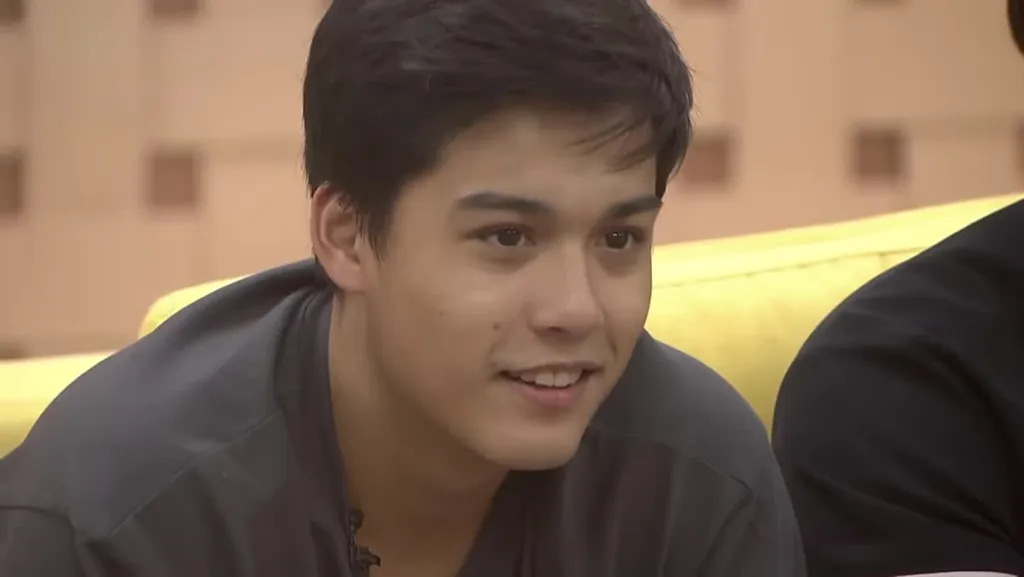 Si Robbie ng PBB Collab 3.0 na nakangiti habang inilalabas ni Mikee ang ukulele